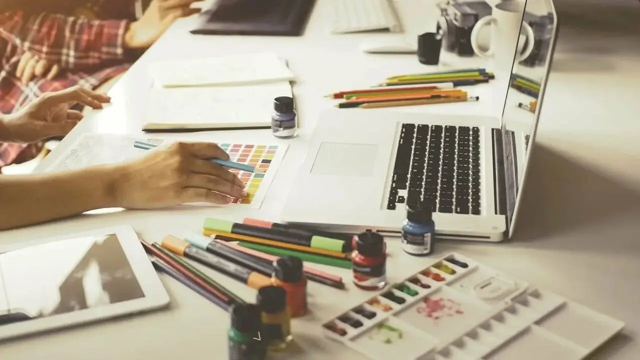 A designer's desk with sketches and a laptop.